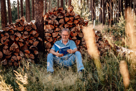 Frank Schmitz sitzt im Wald und liest ein Buch